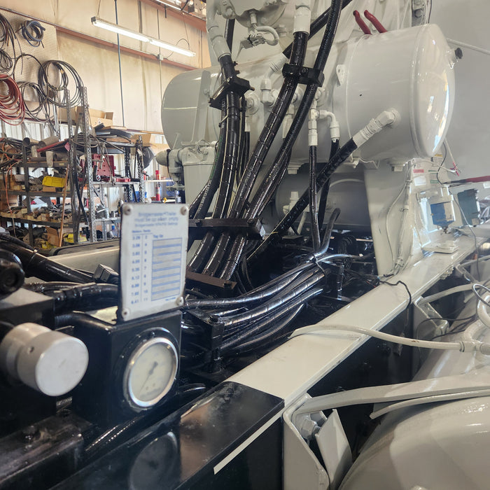 Close-up view of a freshly painted concrete mixer truck in a repair shop, showing detailed hydraulic hoses and components under bright workshop lighting.